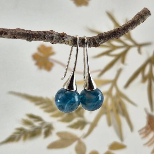 Trompetvormige glazen oorbellen met bolletjes van transparant turquoise/blauw glas met wolk-effect