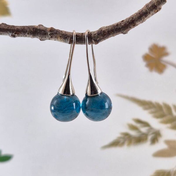 Trompetvormige glazen oorbellen met bolletjes van transparant turquoise/blauw glas met witte streepjes erin