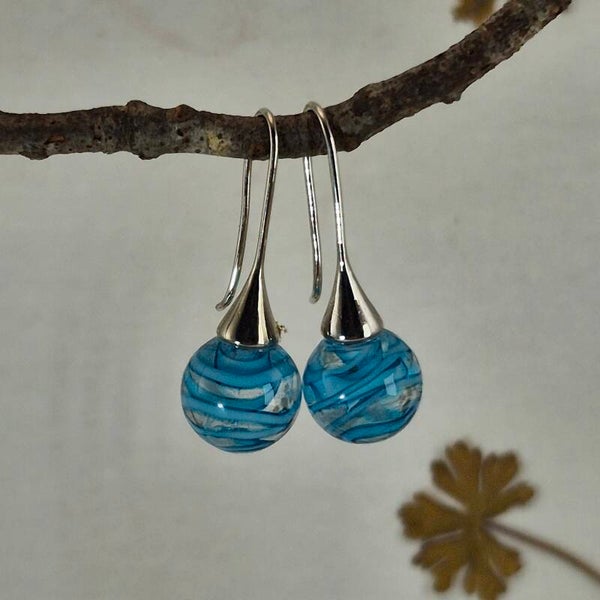 Trompetvormige glazen oorbellen met bolletjes van transparant glas met een turquoise spiraal erin