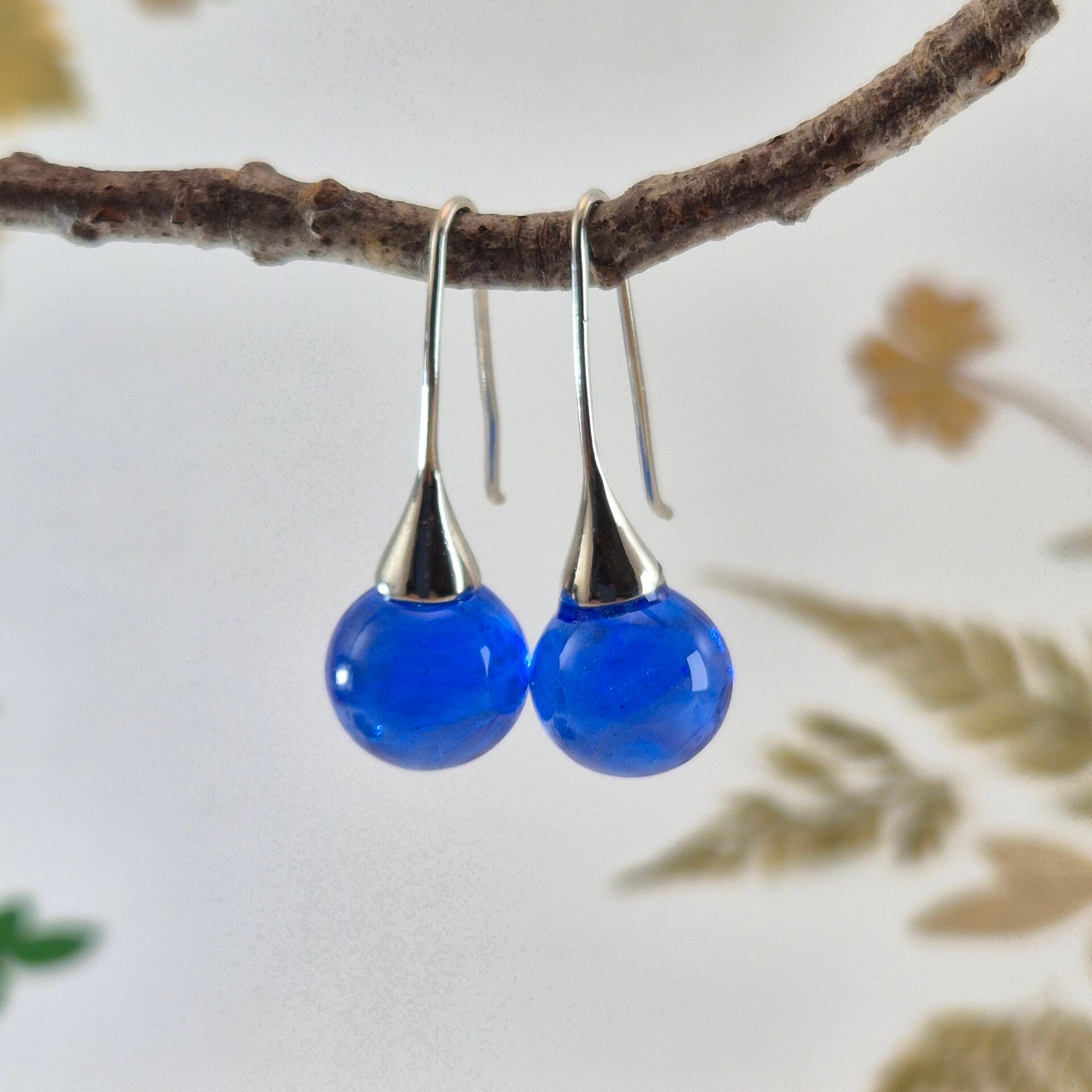 Trompetvormige glazen oorbellen met bolletjes van transparant blauw glas met wolk-effect