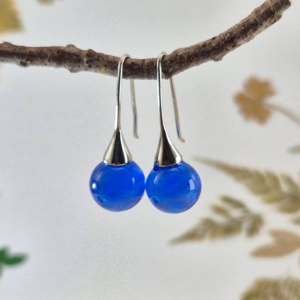 Trompetvormige glazen oorbellen met bolletjes van transparant blauw glas met wolk-effect