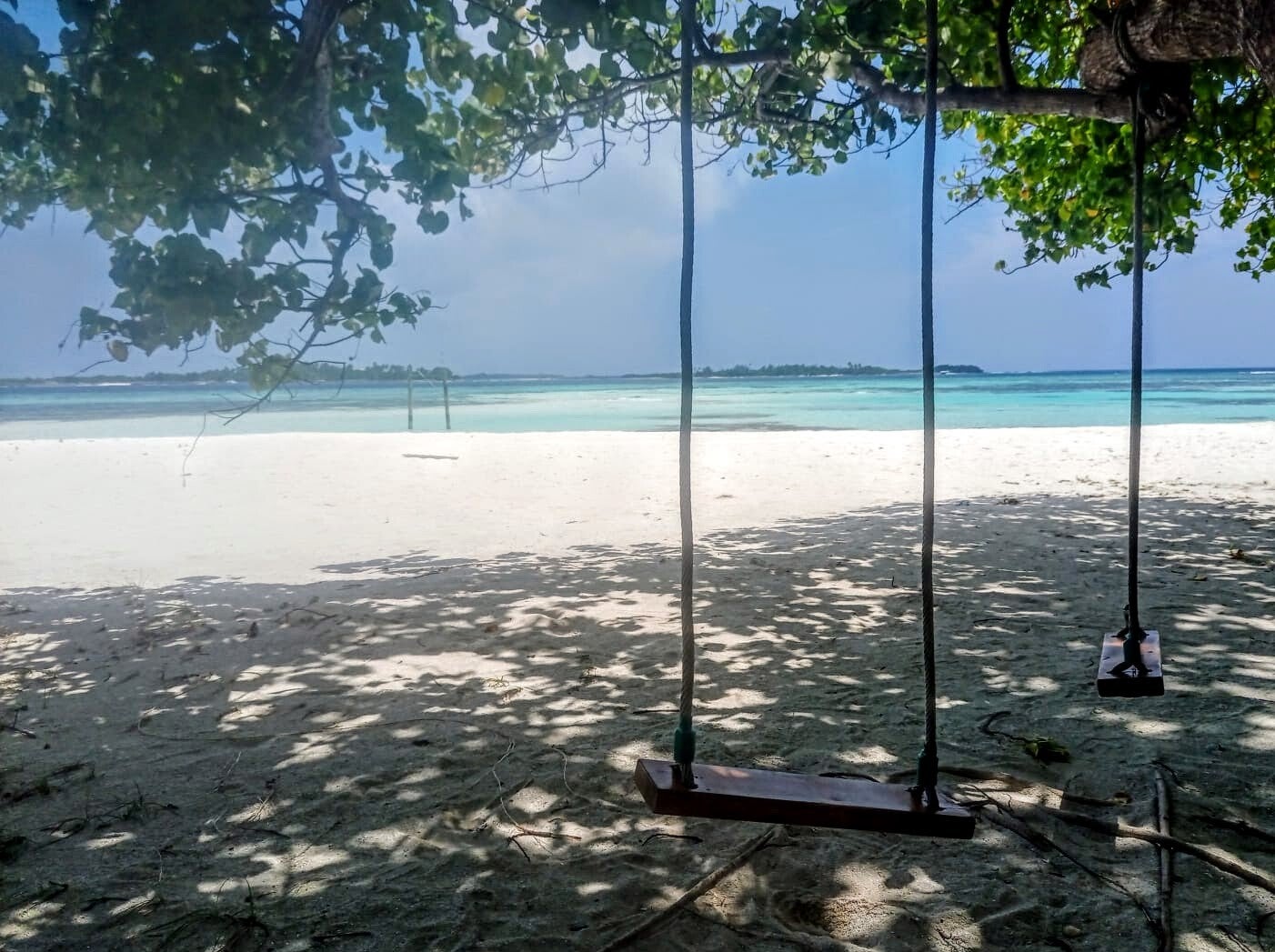 white sandy beach with wooden swings on Himmafushi Maldives