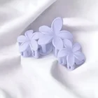 Eine fliederfarbende Haarspnage mit 3 Blüten lieget auf einem weißen Stoff.