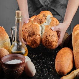 mujer-sosteniendo-pan-sobre-mesa-oscura-con-huevos-tazon-de-harina-y-vaso-de-aceite-standard.jpg