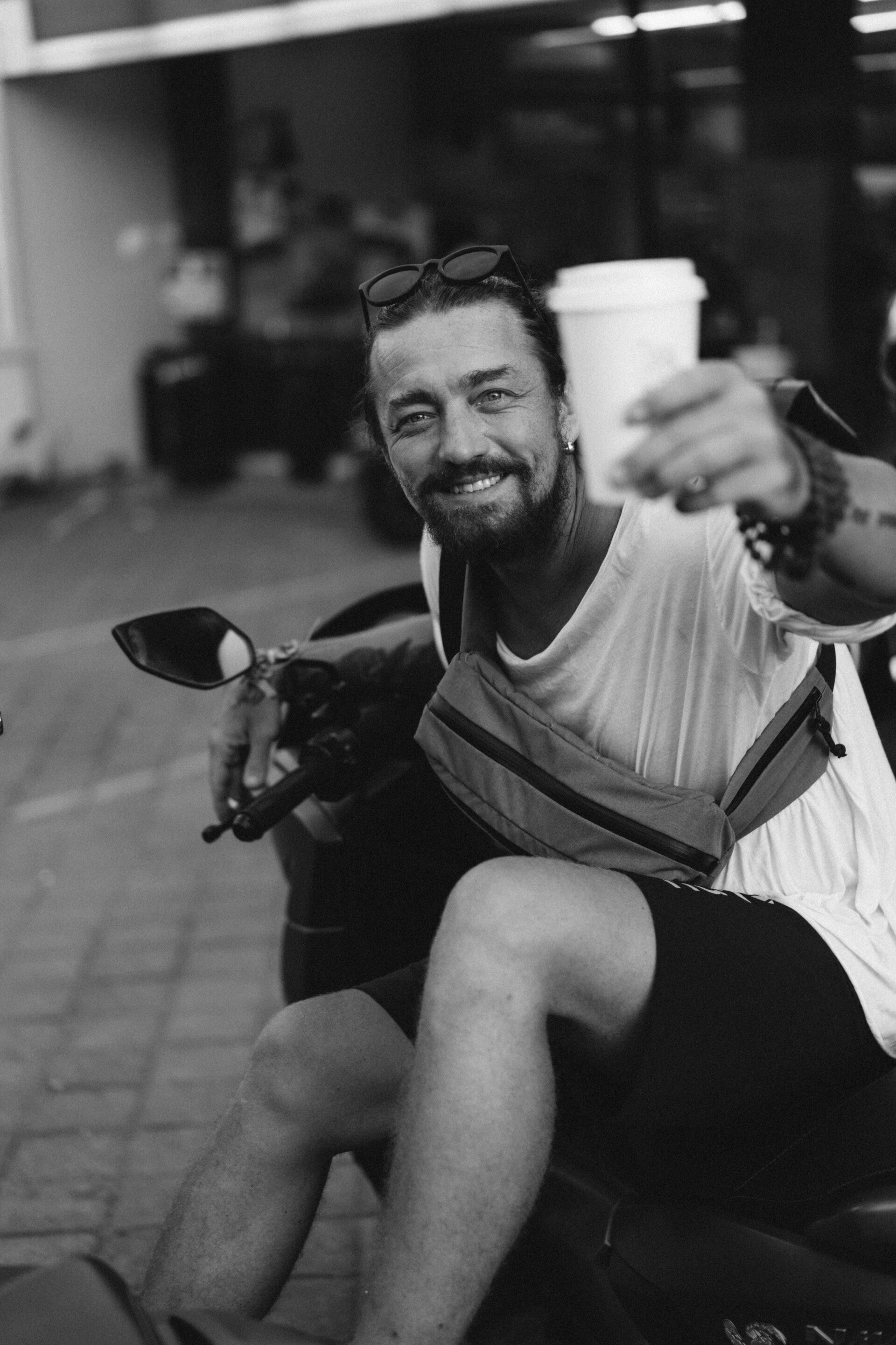young-stylish-man-with-beard-drinks-coffee-from-disposable-paper-cup-sits-motorbike-street-lifestyle-tropical-life-bali-standard.jpg