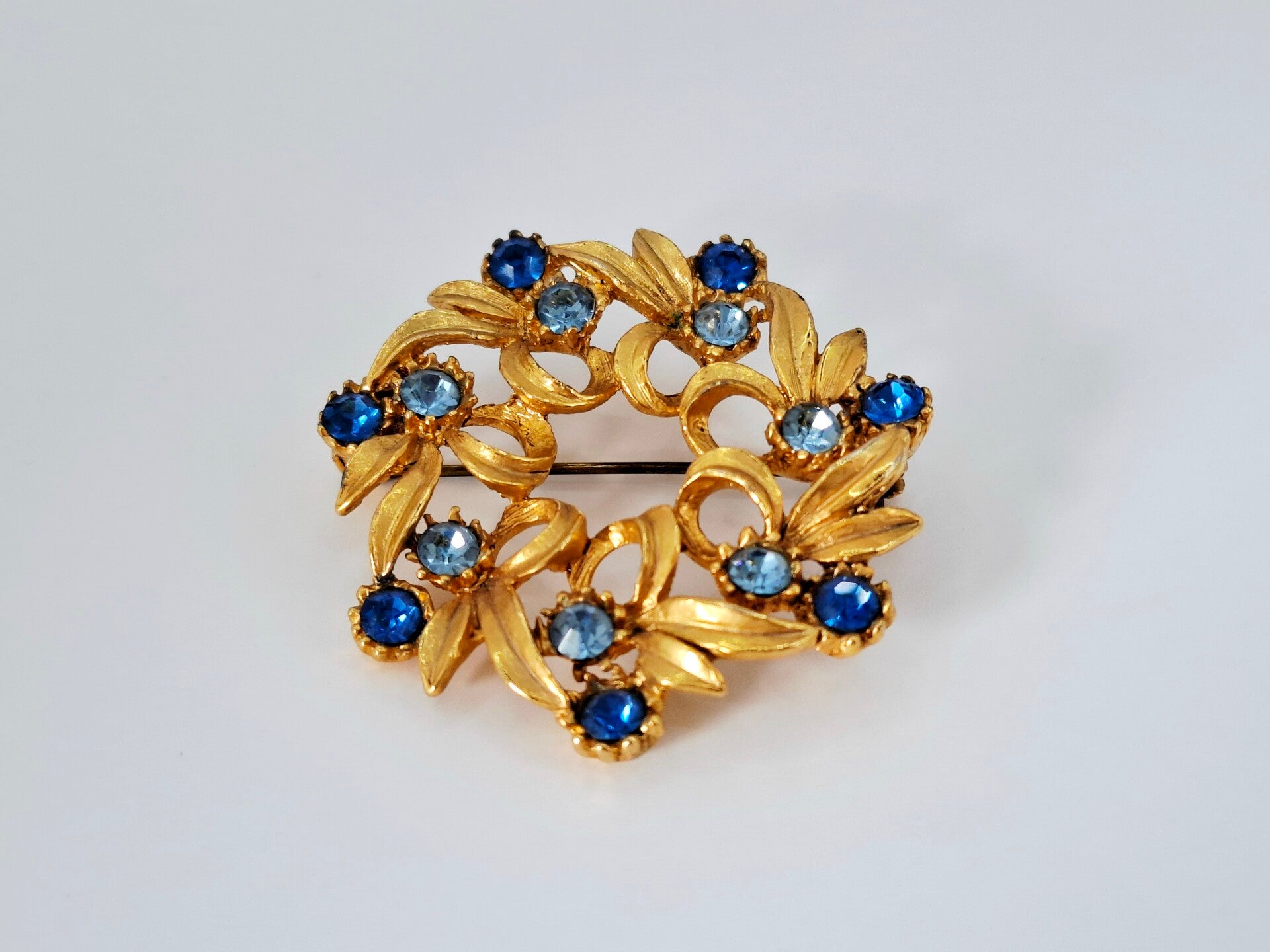 Ronde vintage broche goudkleurig blauwe strass