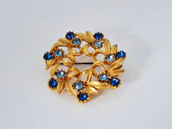 Ronde vintage broche goudkleurig blauwe strass