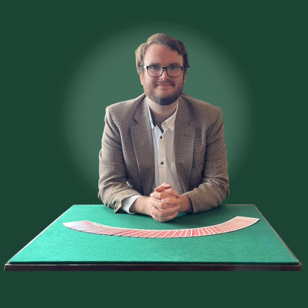 A smiling magician at a table with a deck of cards