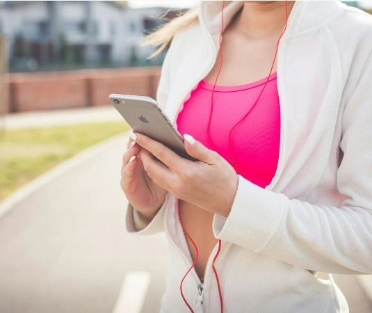 Runner regardant sur son téléphone son programme de course à pied 10km établi par son coach personnel