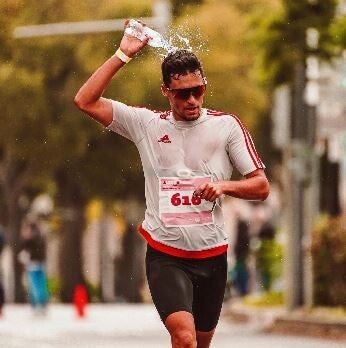 Coureur qui se verse de l'eau sur la tête pour se refroidir