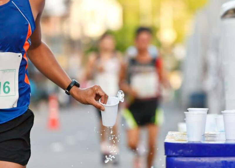 Coureur utilisant le ravitaillement pour s'hydrater en course