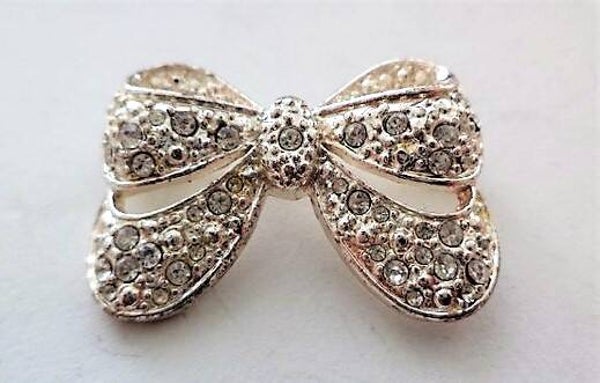 Elegante zilverkleurige Strikbroche met fonkelende Kristallen