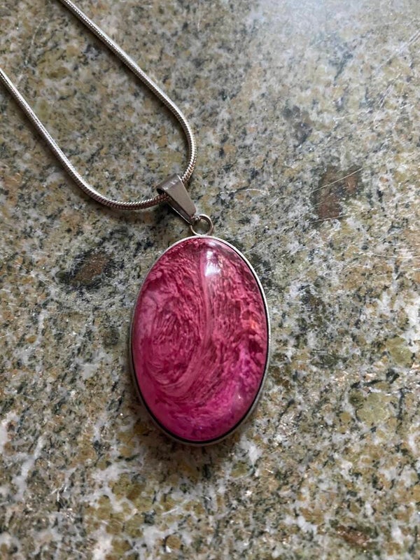 Hängsmycke i röda/rosa toner, ovalt