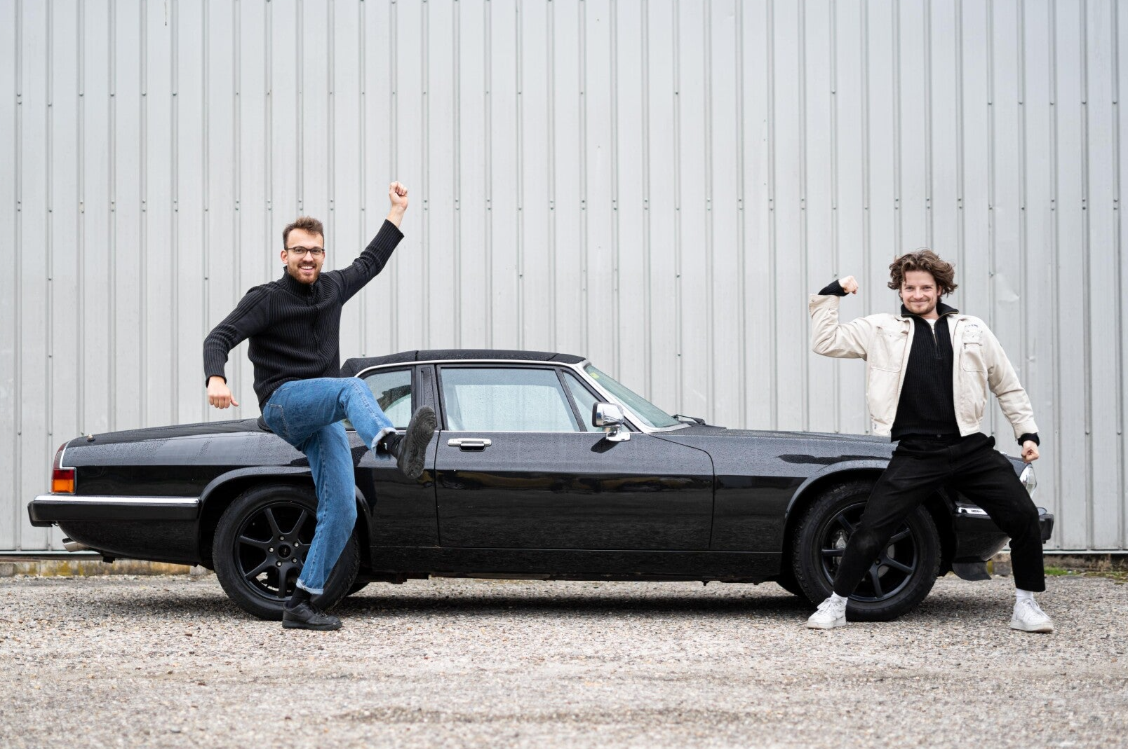 De twee eigenaars van autobedrijf Magalimoto, grappig stralend met een youngtimer