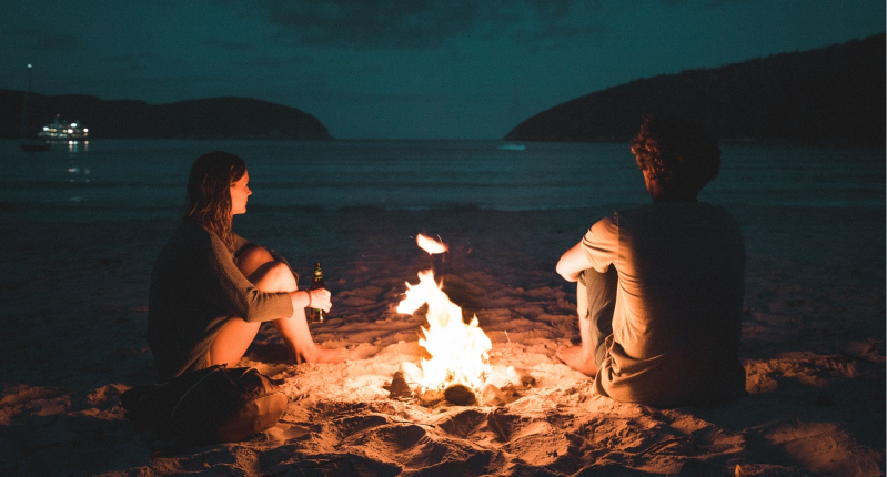Koppel bij kampvuur op een strandje