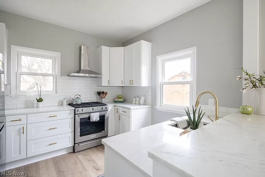 Bright renovated kitchen featuring white shaker cabinets, granite countertops, and farmhouse sink