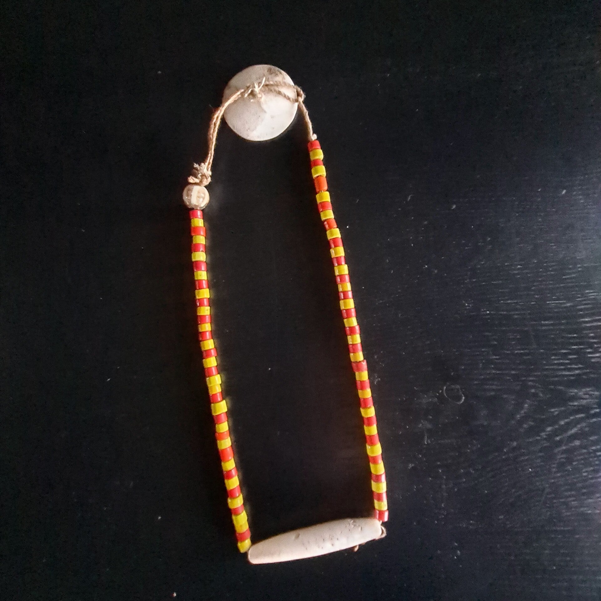 Old nacklace with yellow/red beads with a circulair shaped seashell (#705)