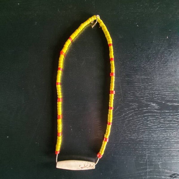 Old nacklace with yellow/red beads with a circulair shaped seashell (#706).