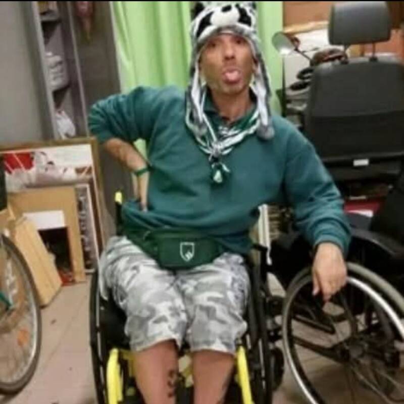 Ragazzo in carrozzina abbigliamento estivo con cappello procione buffo,  espressione del viso con linguaccia 