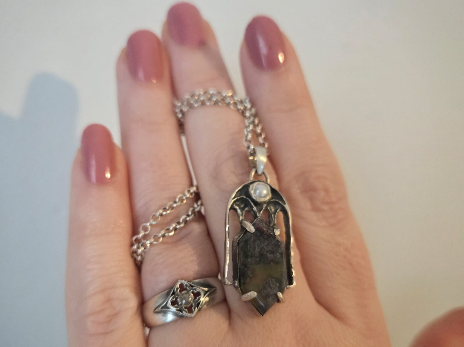 Dark romantic silver jewelry styled on black fabric, handmade in the Netherlands Morningstar pearl pendant in sterling silver with a gothic salt and pepper diamond ring