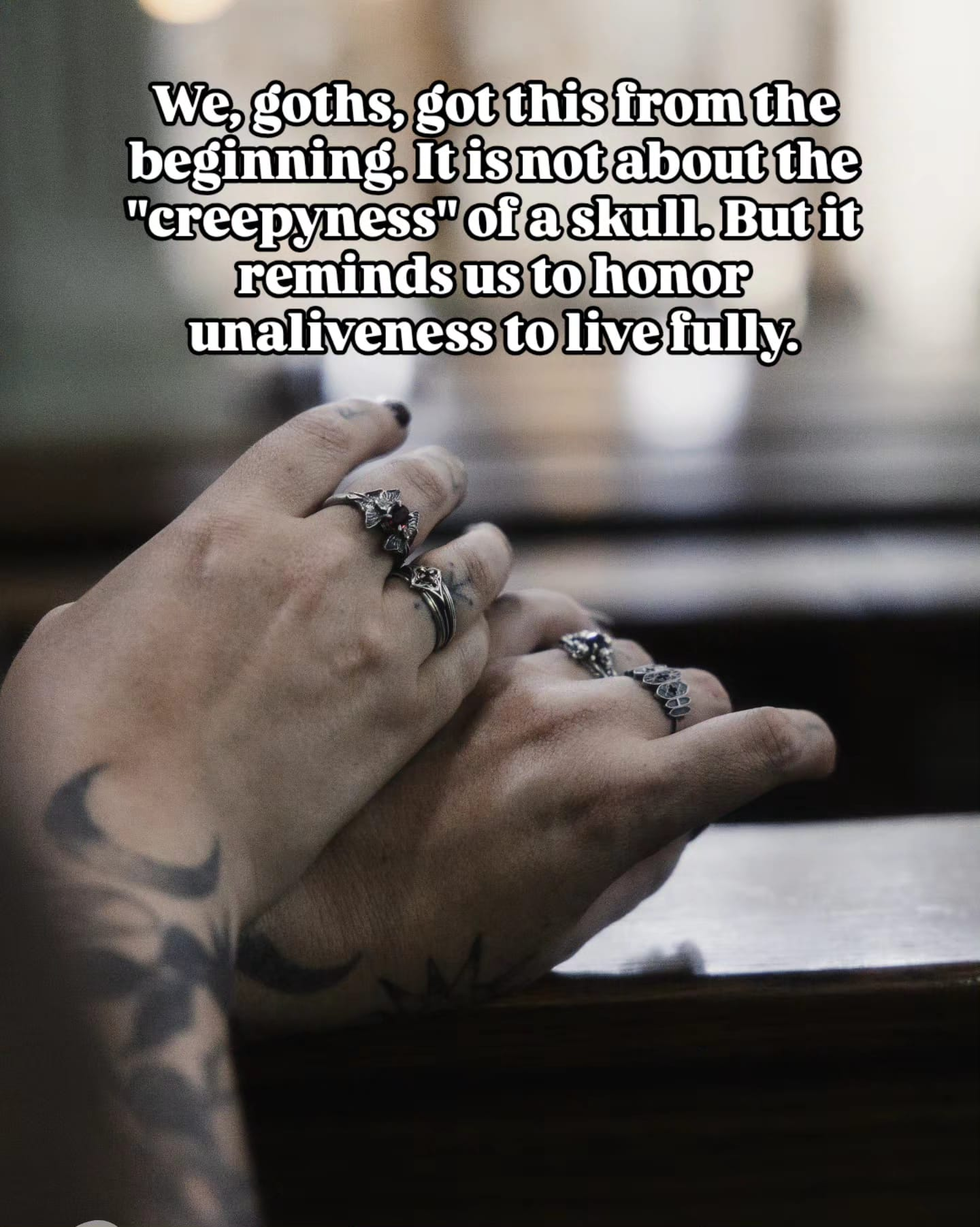 Two tattooed hands resting on a church pew wearing handmade gothic sterling silver rings
