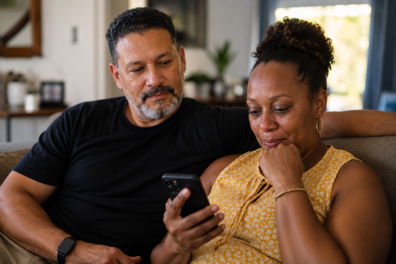 Husband and wife sharing an emotional moment while listening to an old voicemail, highlighting the importance of voice preservation and future memories.