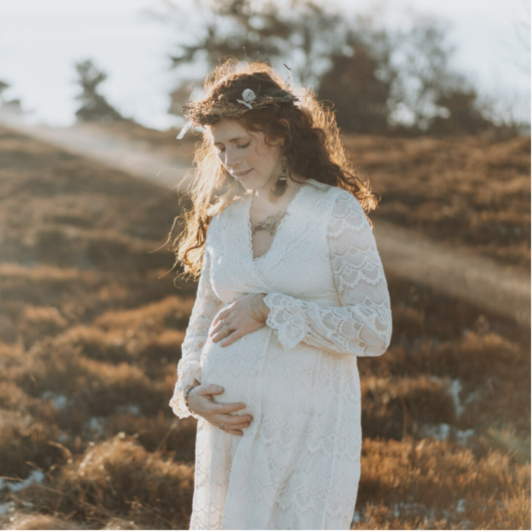 Femme enceinte en robe blanche dans un paysage