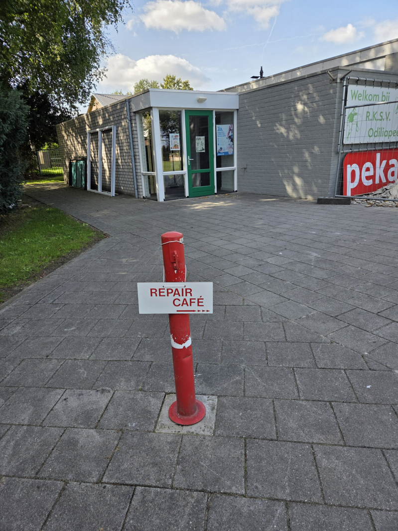 op de foto een paaltje voor de kantine met een verwijzing naar het repaircafé