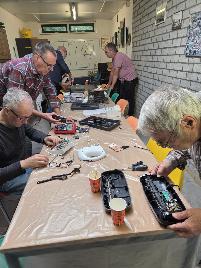 Op de foto wordt gewerkt aan een mixer en een andere vrijwilliger is bezig om een papierversnipperaar weer aan de praat te krijgen