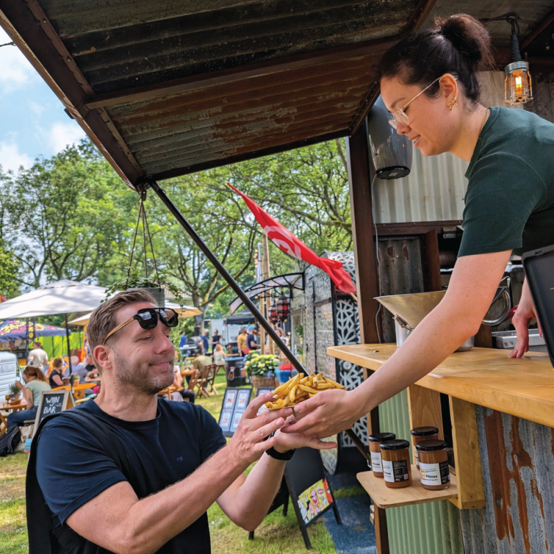 man-pakt-friet-aan-serveren-festival-foodtruck-medewerker
