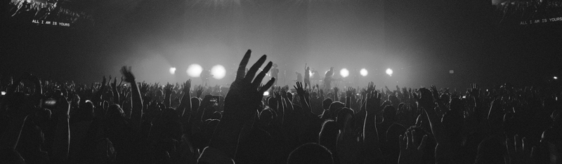 Blick aus dem Publikum auf die Bühne mit gelber Beleuchtung – Live-Band-Performance mit beeindruckender Eventbeleuchtung