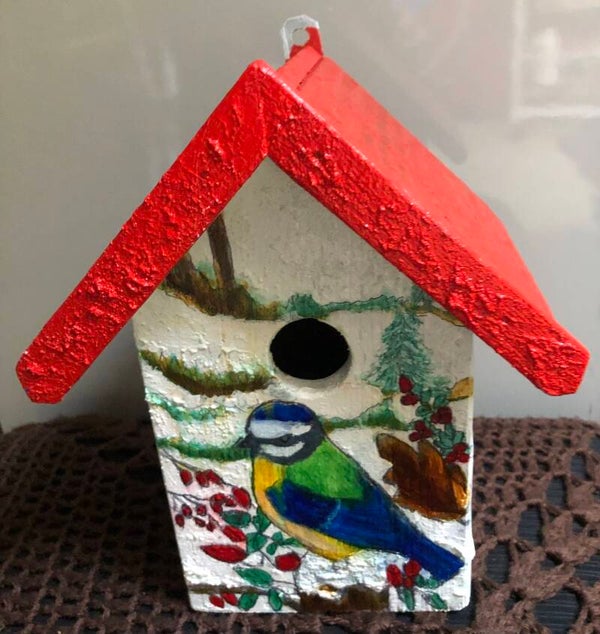 Vogelhuisje met vogel in de sneeuw
