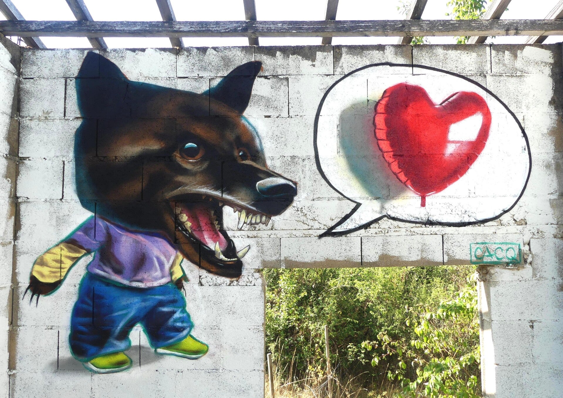 Peinture à la spray sur un mur représentant un enfant à tête de chien-loup en train de dire quelque chose. Une bulle de BD à côté contient un ballon gonflable en forme de cœur. Street-art.