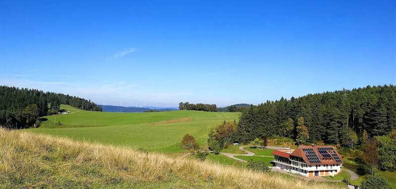 Ein entfernter Blick auf die Unterkunft für den Aktivurlaub inmitten von weiten Wiesen und Wäldern.