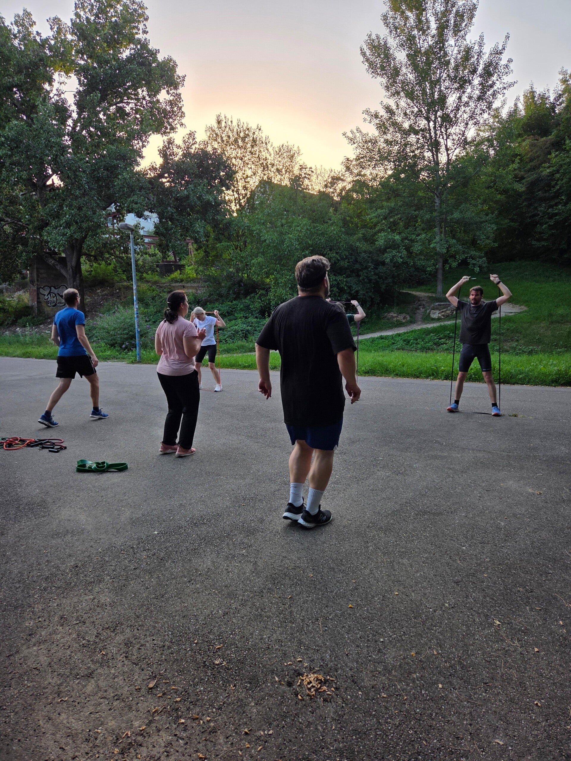 Die Trainingsgruppe sitzt im Kreis auf Yogamatten und macht ein cool down nach der Trainingseinheit draußen in der Natur.