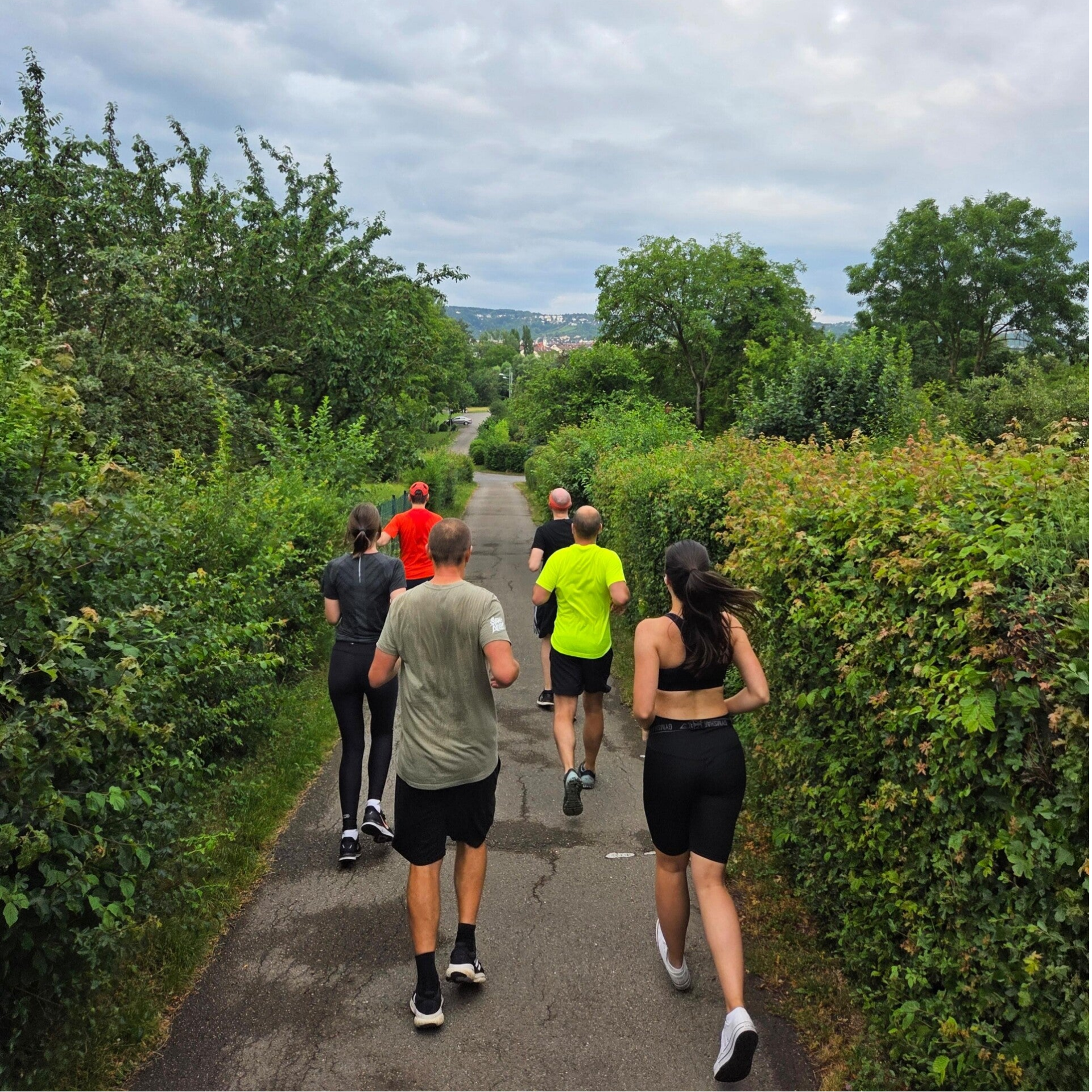 Die Mitarbeitenden einer Firma joggen durch Felder und haben viel Freude dabei.