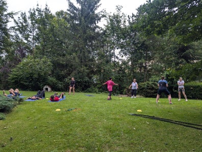 Die Gruppe macht verschiendene Übungen im Zirkeltraining mit einem Battle Rope, Yogamatten, Hütchen und Bällen.