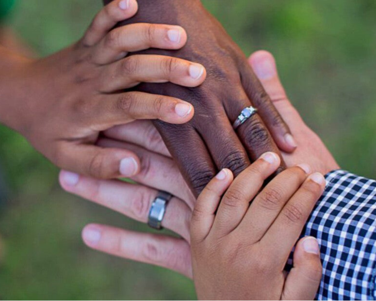 Verschillende handen van ouders en kinderen op elkaar als symbool van adoptie, liefde en verbondenheid