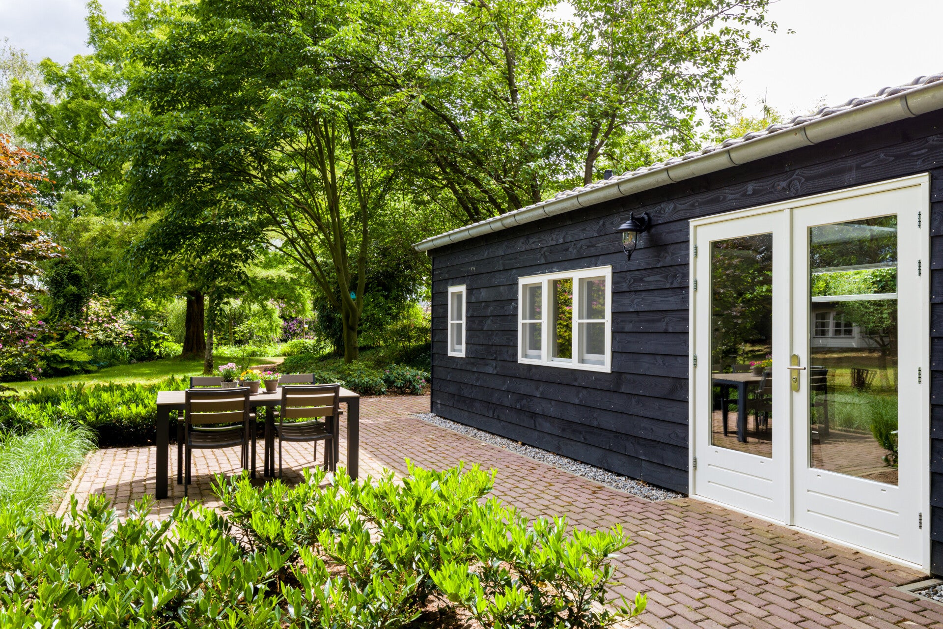 Rustige praktijkruimte in groene omgeving met terras en tafel, waar cliënten in een veilige sfeer kunnen praten over hun adoptieverhaal.
