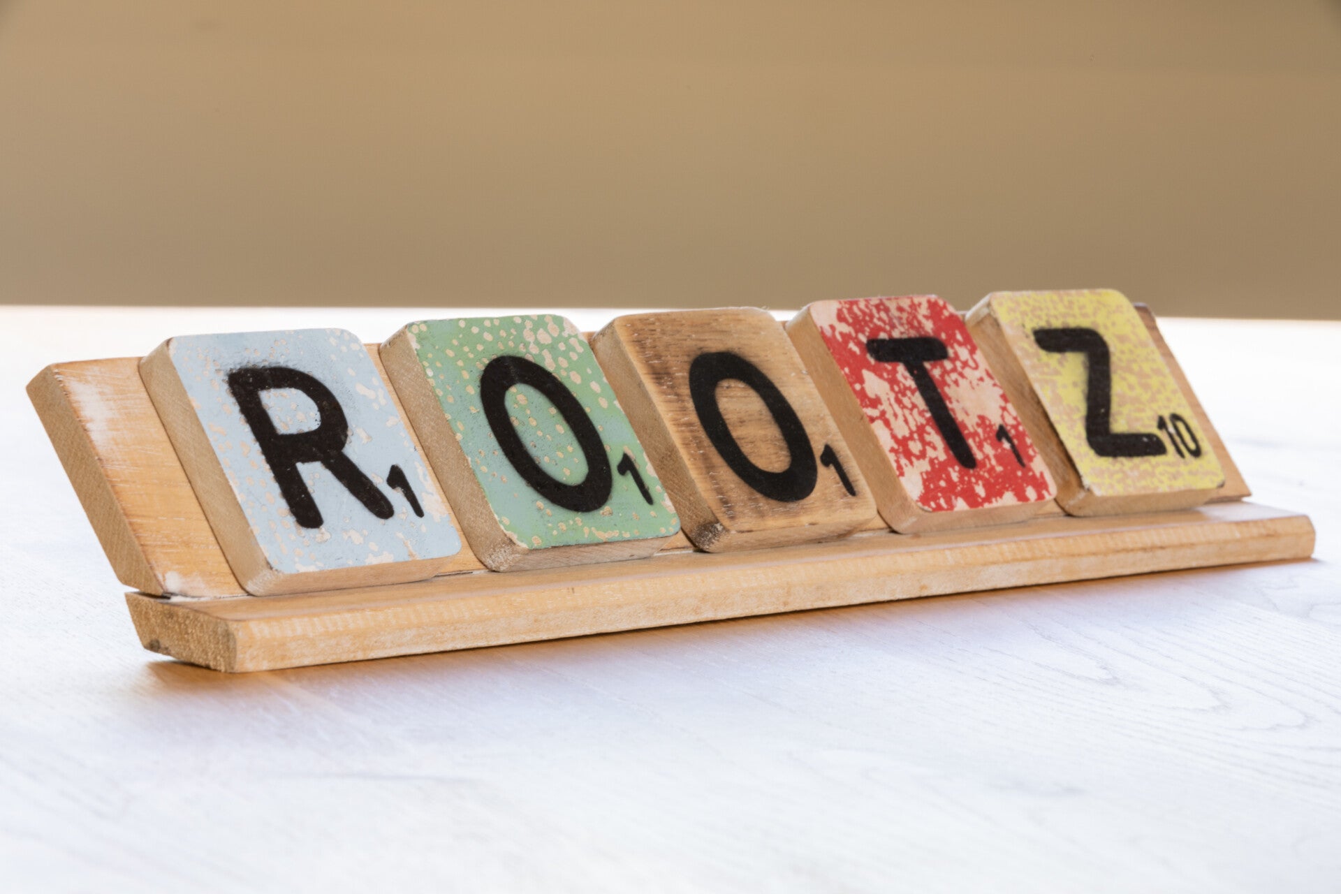 Houten scrabbleletters die samen het woord “ROOTZ” vormen, symbool voor verbinding met je oorsprong en identiteit
