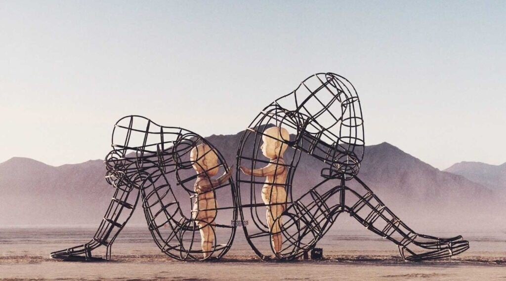 Symbolische kunst van twee metalen figuren die met de rug naar elkaar toe zitten, terwijl twee innerlijke kinderen elkaar proberen te bereiken. Beeld dat de innerlijke strijd, pijn en het verlangen naar verbinding uitdrukt bij adoptie en persoonlijke groe