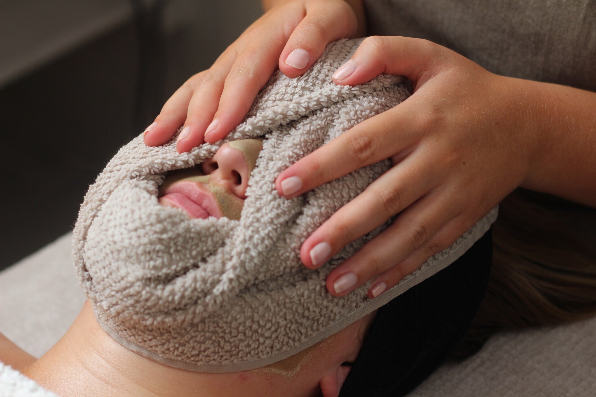 Een warme handdoek ligt comfortabel op het gezicht van een vrouw tijdens een gezichtsbehandeling bij Silk Schoonheidssalon.