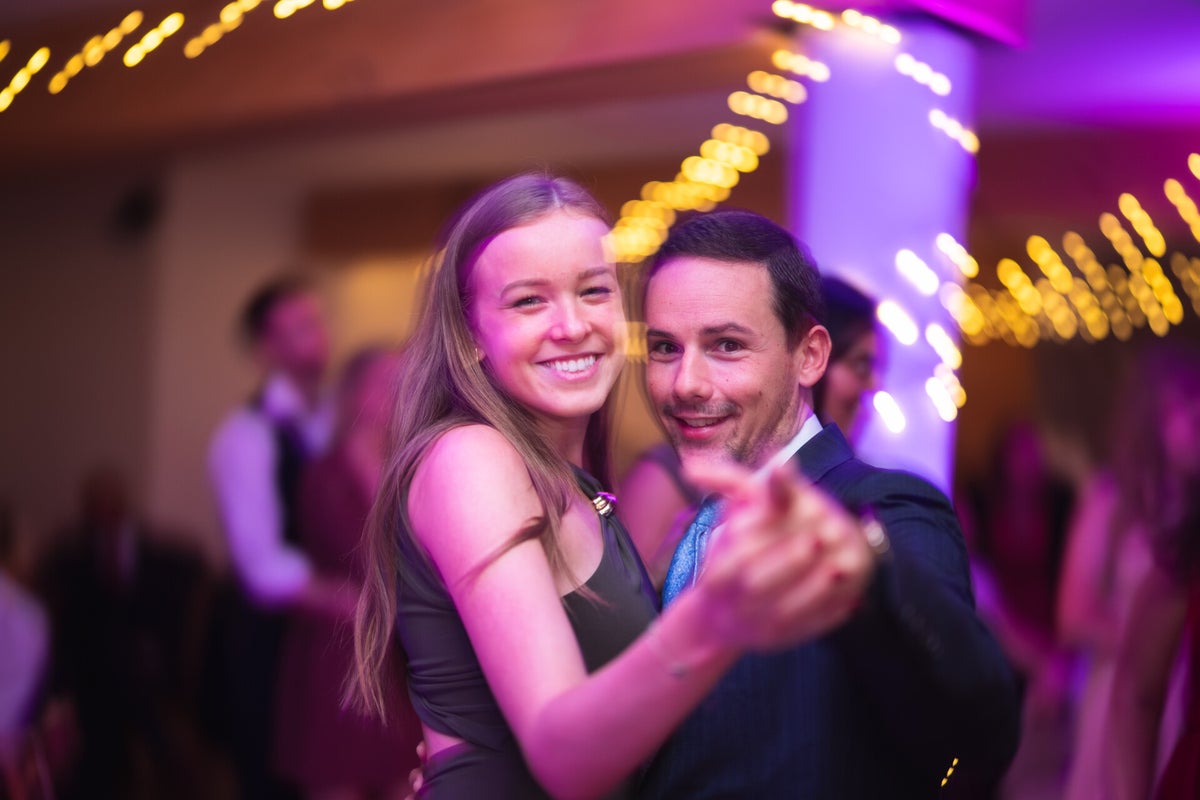 Deux invités sourient sur la piste de danse sous les lumières de la soirée