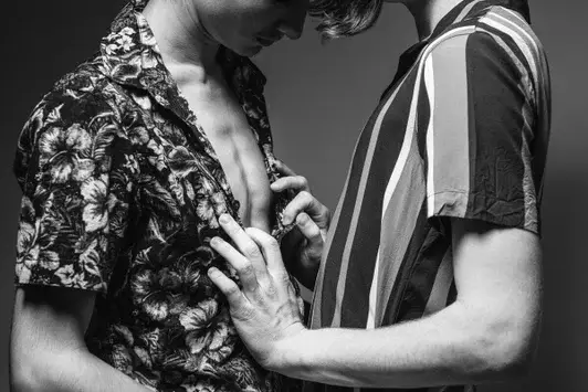 Kunstwerk TENDENCY : Twee mannen in bloemen- en gestreept overhemd, handen rustend op elkaars borst, zwart-wit fotografie met sterke contrasten.