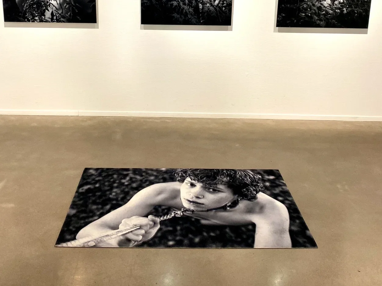 Detailopname van textielkunst op vloer tijdens expositie, textuur van tapijt en zwart-wit contrast zichtbaar in ruimte.