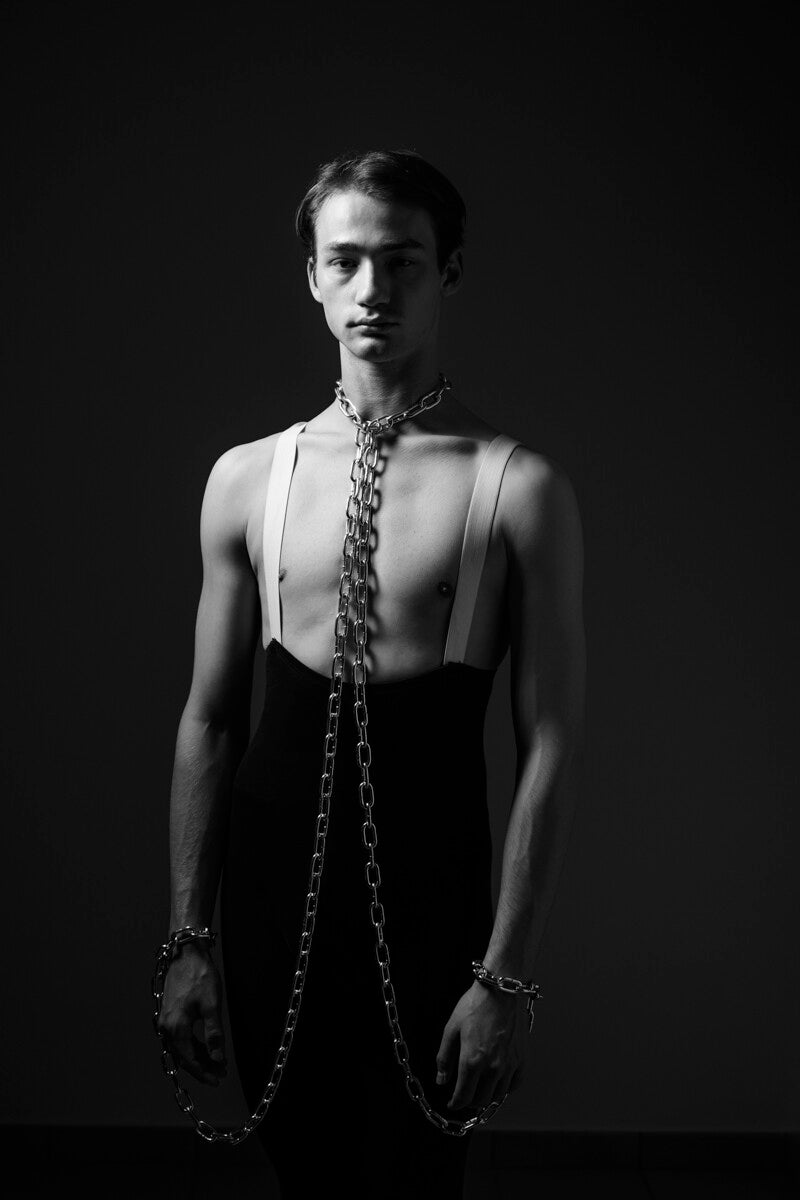 Zwart-wit fine art portret van Arjan Spannenburg. Danser Maksim met kettingen om de nek symboliseert mentale strijd en kracht.