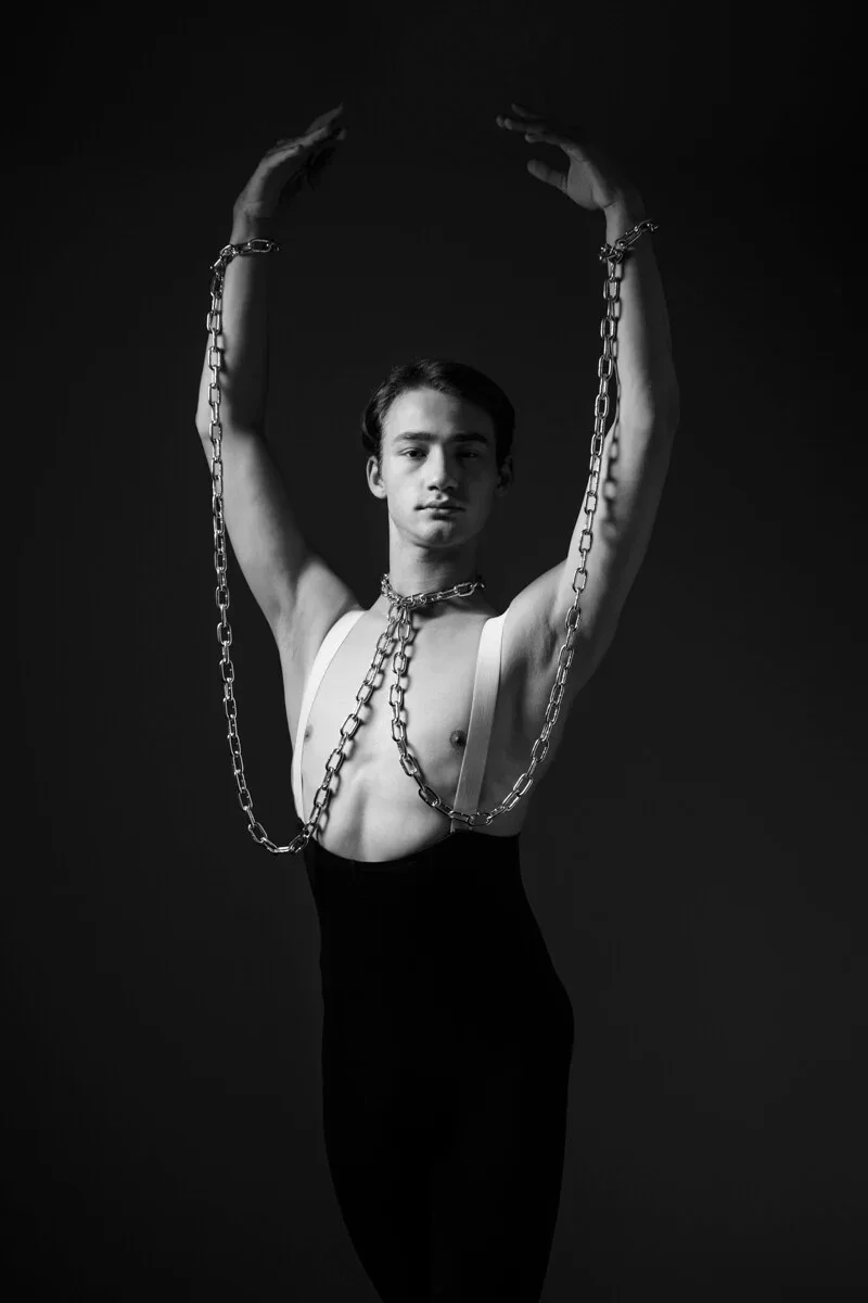 Fine Art foto door Arjan Spannenburg van danser met geheven armen in ketens, toont kwetsbaarheid en de wil om los te breken.