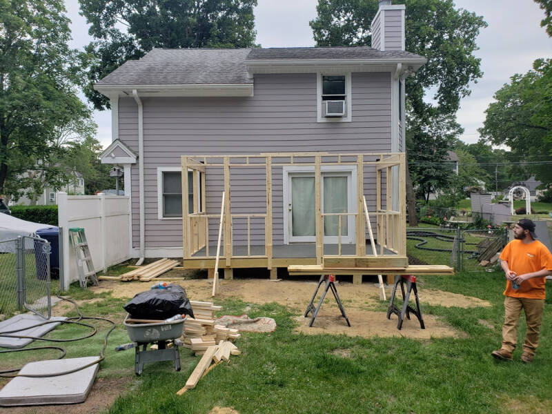 Addition wrapped with weather barrier during exterior construction before siding installation.