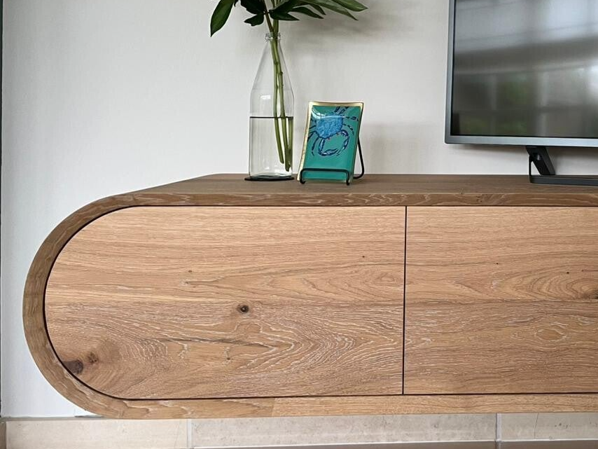 Detail van gebogen TV-meubel met 45-graden rand en strak geïntegreerde kleppen