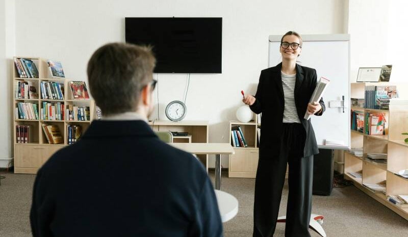 Mujer profesional practicando una presentación frente a un compañero de trabajo